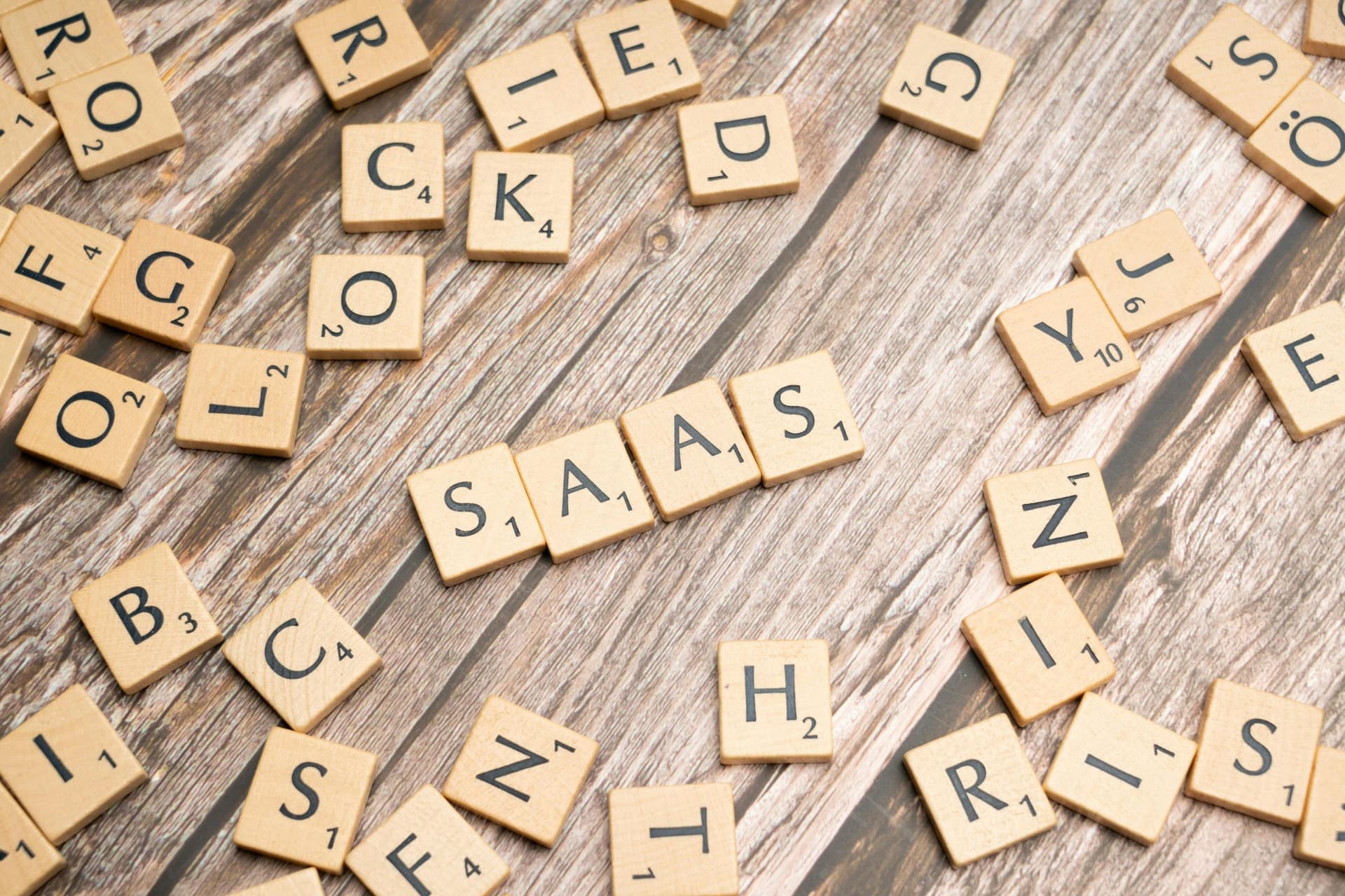 Scrabble letter tiles spelling SaaS on a wooden surface, symbolising Software as a Service innovation in logistics and technology